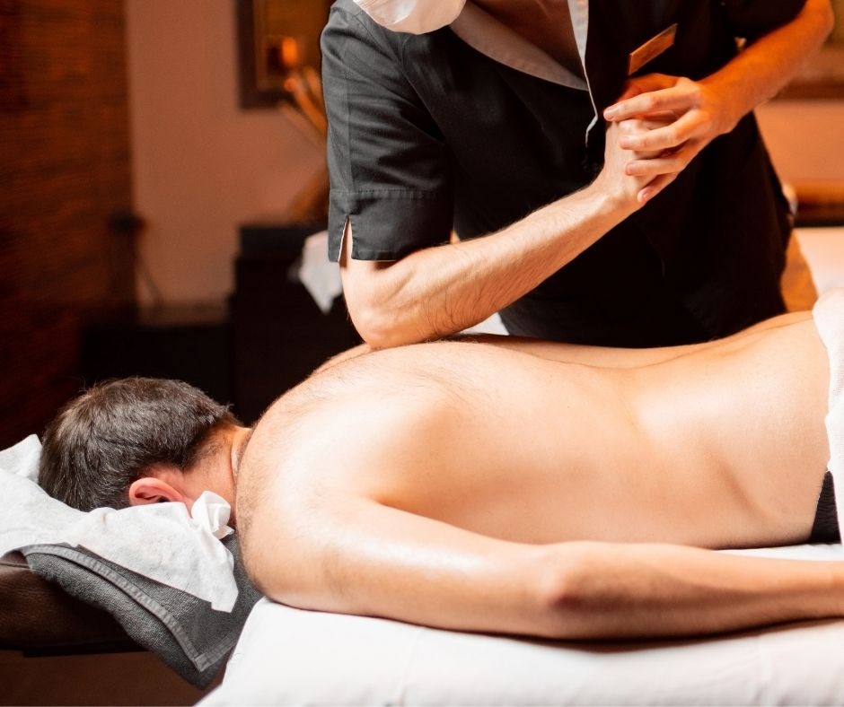a male masseur applying pressure on the back of a male customer